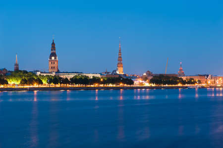 Skyline of Riga seen across the river Daugava after the sunset. Three church towers in the picture are the Riga Dome cathedral,  St. Saviour's Church and St. Peter's church. On the right is railway bridge and broadcast towerの写真素材