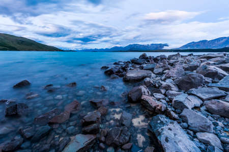 Beautiful dramatic sunset over the incredibly blue lake Tekapo with mountains, Southern Alps, on the horizon. New Zealandの写真素材