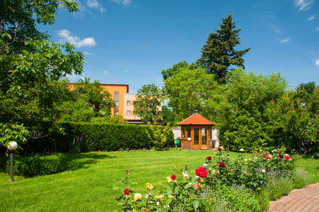 Beautiful garden with blooming roses, brick path and a small gazeboの写真素材