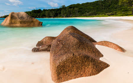 Beautifully shaped granite boulders in the turquoise sea (daytime long exposure technique) at Anse Coco, La Digue island, Seychellesの写真素材