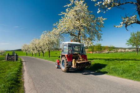 Tractor on the road in the spring countryの写真素材