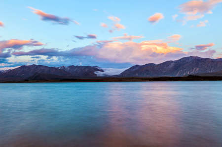 Beautiful dramatic sunset over the incredibly blue lake Tekapo with fog rolling from the mountains. Canterbury region, New Zealandの写真素材