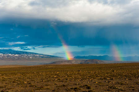 Mountains covered by icy glaciers on Iceland and rainy clouds with rainbowの写真素材