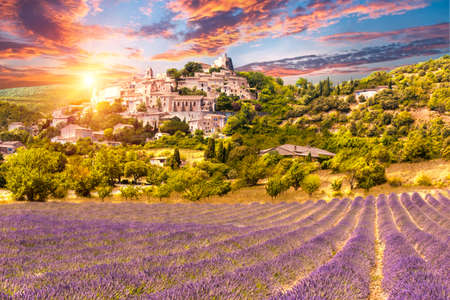 Small but beautiful old town of Simiane la Rotonde with a lavender field in front of it, Provence - France. Sunset timeの写真素材