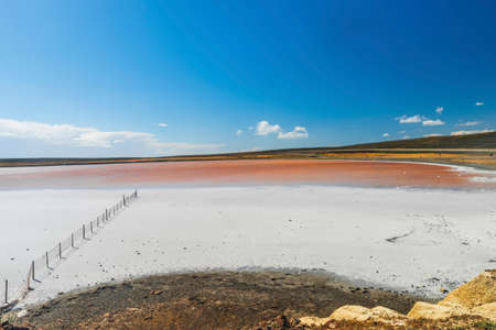 old rusty fence in a salt lake with crystal coated stones in Tierra del Fuego in Argentina.