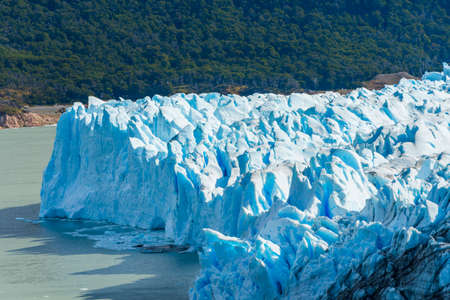 Mighty turquoise ice of Perito Moreno glacier and a tiny tourist ship on the right. Los Glaciares...