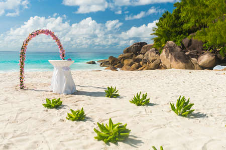 Floral garland and a white table as wedding decorations on a tropical beach Anse Georgette on Praslin island in the Seychellesの写真素材