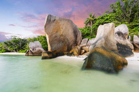 Beautifully shaped granite boulders and a dramatic sunset at Anse Source d'Argent beach, La Digue island, Seychelles.の写真素材