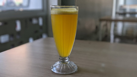 A glass of orange juice on a wooden table in a cafe.
