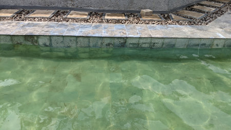 Water surface in the pool with stone stairway and green water backgroundの写真素材