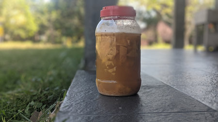 A jar of ice tea on the grass in the garden. Selective focus.