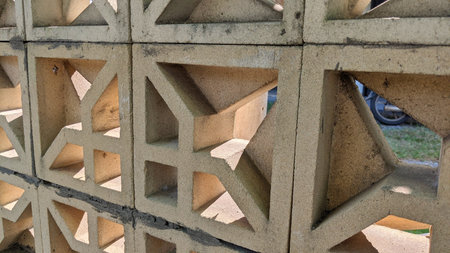 Sunlight penetrates between the house fence which has holes in it.