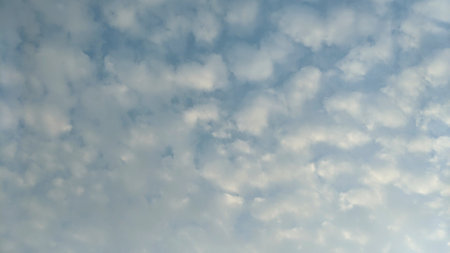 A blue sky with numerous small, white clouds. The clouds are arranged in a grid-like pattern,...