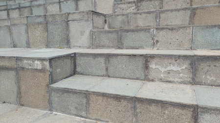 An outdoor stone staircase with multiple broad steps, featuring a muted gray and green palette, showing some wear and natural texture.の写真素材