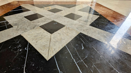 An exquisite marble floor showcasing a geometric pattern with black, white, and reddish-brown polished tiles, creating a sophisticated and luxurious aesthetic.の写真素材