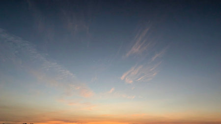A sunrise sky over Indonesia, transitioning from deep blue to soft orange, with wispy clouds and a single bright star visible.の写真素材