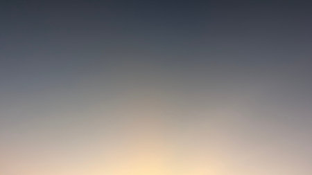 A soft sunrise sky displays a subtle gradient from deep blue-gray to a warm, pale orange, with a...