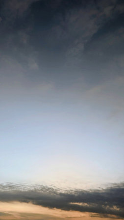 A vertical shot capturing the vast sky's gradient from dark, moody clouds at the top to a clear,...