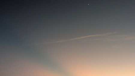 A beautiful gradient sky, transitioning from dark blue to vibrant orange and yellow, with a few...