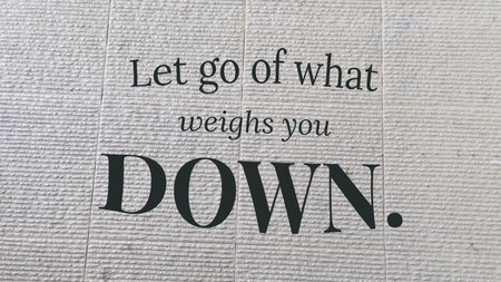 An inspiring message, Let go of what weighs you DOWN. on a textured, light-colored background.
