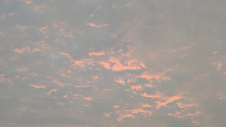 A serene sky filled with scattered, textured clouds, washed with a soft pink and gray palette. The...