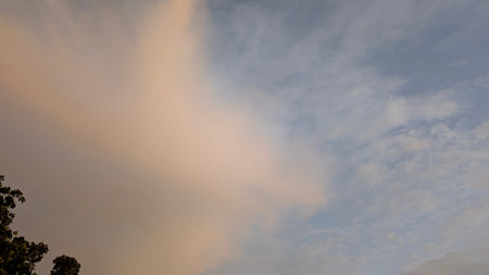 A peaceful sky with a large, soft cloud of pale pink and orange on the left. The right side is a...