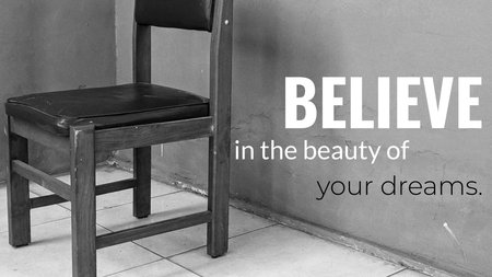 A black and white image of an empty wooden chair sitting on a tiled floor next to a worn, textured wall. A quote is superimposed &quot;BELIEVE in the beauty of your dreams.&quot;の写真素材