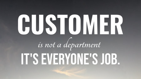A powerful black and white image displays the text &quot;CUSTOMER is not a department IT&#39;S EVERYONE&#39;S JOB.&quot; The bold message is set against a cloudy, blurry sky backdrop.の写真素材