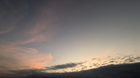 A tranquil dawn scene with a bank of dark clouds at the bottom. The sky above transitions from soft...