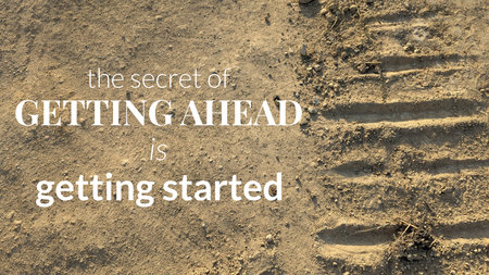 A quote reads, &#39;The secret of GETTING AHEAD is getting started&#39;. The text is positioned on a light brown, dusty ground with a deep tire track and scattered pebbles to the right.の写真素材