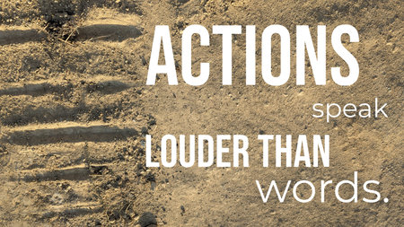 A motivational quote is laid over a sandy, textured ground with tire tracks. The text reads "ACTIONS speak LOUDER THAN words," with the main words emphasized to highlight the quote's meaning.の写真素材