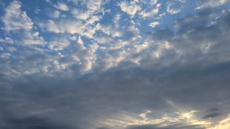 A striking sky with layers of clouds. Darker, heavy clouds dominate the bottom, while above them,...