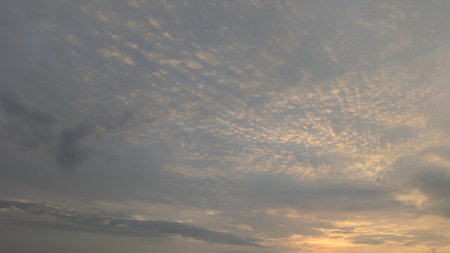 A close-up view of the sky with textured clouds and hints of orange and yellow light.の写真素材