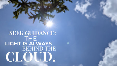 A brilliant sun shines through a tree branch against a blue sky, featuring the quote, &quot;SEEK GUIDANCE, THE LIGHT IS ALWAYS BEHIND THE CLOUD.&quot; This image suggests enduring hope divine presence.の写真素材
