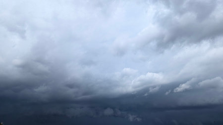 A dramatic sky view featuring thick, dark cumulonimbus clouds. The contrast between light gray above...