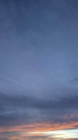 Sky displays soft, subtle cloud patches in deep indigo, muted blue, gray tones. A thin horizontal...