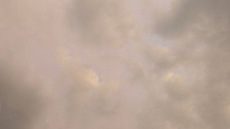 Moody overcast sky shows dense grey, tan clouds. Soft light filters through heavy vapor, creating a...