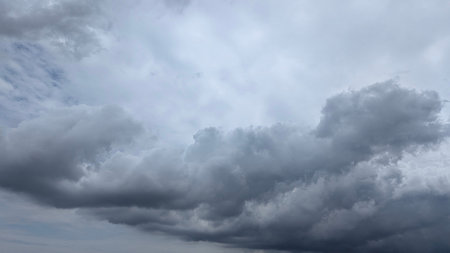 A dramatic wide shot captures a vast expanse of dark, heavy storm clouds filling the sky. Layers of...