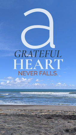 An inspirational quote, a GRATEFUL HEART NEVER FALLS, appears over a scenic coastal background. The image displays a vast blue sky with fluffy white clouds above rolling ocean waves. The foreground features dark volcanic sand. Typography uses white plus orange colors to emphasize this spiritual message.