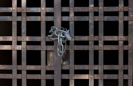 Old grid door locked by a chainの写真素材