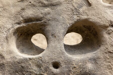 Strange head shaped holes in a cliffの写真素材