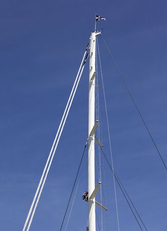 Man climbing the mast of a large sail boatの写真素材