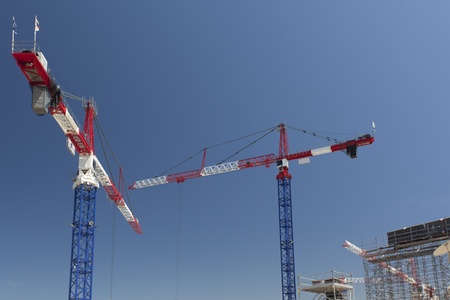 Red and white cranes on a construction siteの写真素材