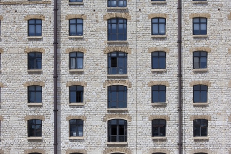 Facade of an old style stone building showing a symmetric array of windowの写真素材
