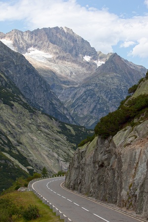 Curvy road in the Swiss Alps with snow and mountains in the backgroundの写真素材