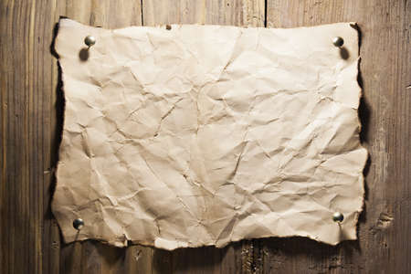 Old crumpled paper nailed to a wooden wallの写真素材