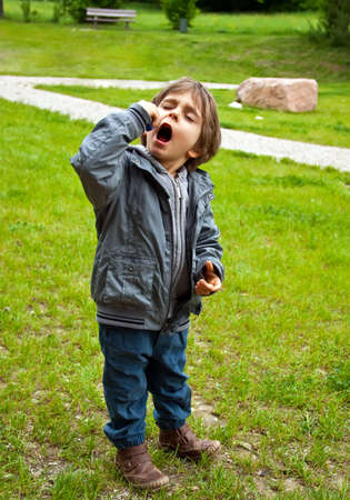 Little boy eats sweets. He covered his eyes with pleasure.の写真素材