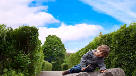 A little boy sitting on a rock.の写真素材