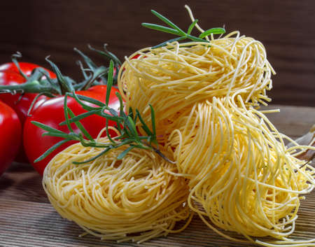 Pasta  and tomatoes on a wooden tableの写真素材