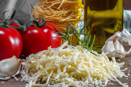 Grated cheese and tomatoes on a boardの写真素材